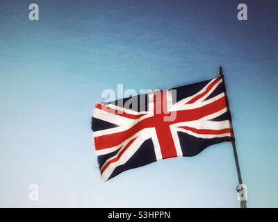 Le drapeau du Royaume-Uni flotte fièrement dans un ciel bleu avec un grand rétro-éclairage. Photo ©️ COLIN HOSKINS. Banque D'Images