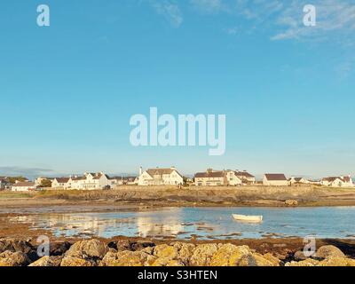 Plage de Rhosneigr début de soirée fin août alors que le soleil se couche sur les maisons, donnant sur le village depuis la plage en face de la piscine à bateaux, Anglesey, au nord du pays de Galles, Royaume-Uni Banque D'Images