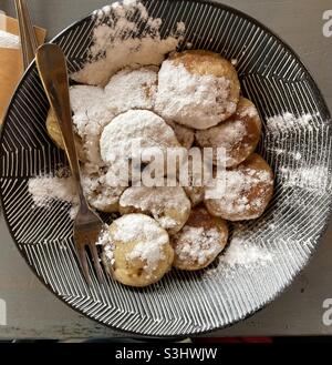 une assiette à motifs noire et blanche avec des poffertjes et du sucre en poudre ainsi qu'une fourchette Banque D'Images