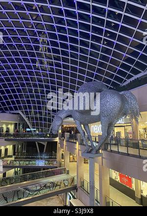 Trinity Leeds, la nuit, un grand centre de vente au détail et de loisirs à Leeds, Royaume-Uni. Nommé d'après l'église Sainte-Trinité voisine, un bâtiment classé de classe I de 1722-7. La sculpture de ‘Equi Altus’ est réalisée par Andy Scott. Banque D'Images