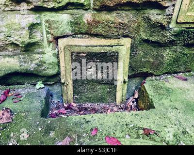 une vieille porte de mousse dans un mur de pierre humide Banque D'Images