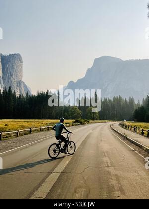 Un homme fait du vélo dans la basse vallée de Yosemite avec une vue magnifique sur Half Dome. Parc national de Yosemite, Californie, États-Unis. Banque D'Images