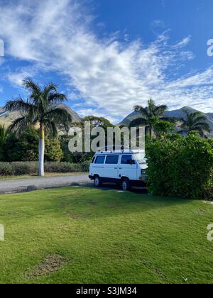 Fourgonnette VW garée en face des montagnes de Maui entourée de palmiers. Banque D'Images