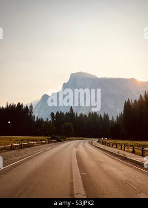 Tôt le matin et route vide sur la Yosemite Valley, le demi-dôme emblématique en arrière-plan.Parc national de Yosemite, Californie, États-Unis. Banque D'Images