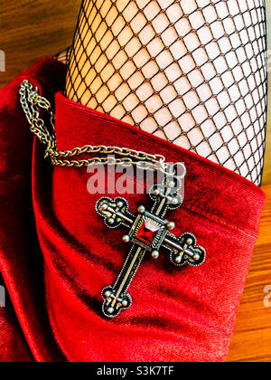 Collier en croix argenté sur la jambe d’une femme Banque D'Images