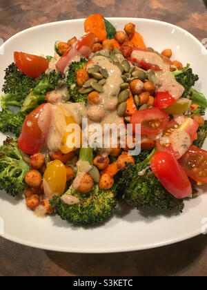 Délicieux bol de légumes végétaliens avec brocoli, tomates, pois chiches rôtis et carottes, recouvert de pepitas. Banque D'Images