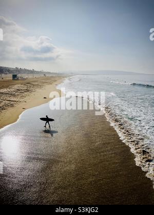 Un surfeur se promène sur la plage après le surf.Manhattan Beach, Californie, États-Unis. Banque D'Images