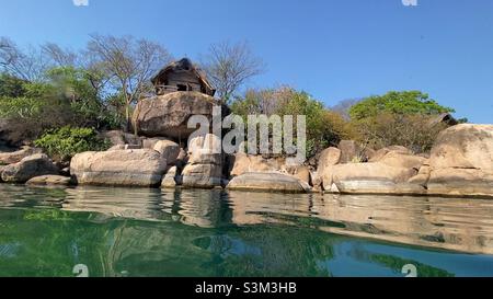 Une hutte de chaume pittoresque et rustique perchée sur un immense Boulder surplombant l'eau du lac Malawi. Banque D'Images