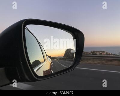 Coucher de soleil sur la mer reflété dans le miroir d'aile de voiture Banque D'Images