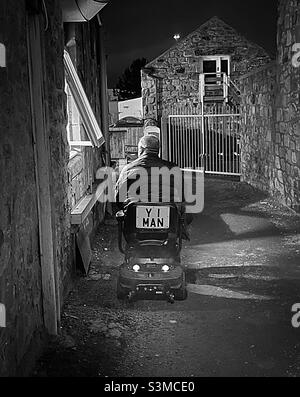 "Why Aye Man" un gentleman Northumbrien local à bord d'un scooter de mobilité ramasse ses Fish & chips de sa propre trappe de service spéciale Banque D'Images