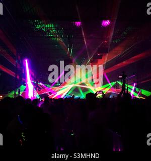 Silhouettes de personnes et lasers lors d'une fête de musique de danse électronique. Banque D'Images