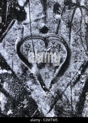 Un coeur dessiné dans la neige sur un étang gelé. Banque D'Images