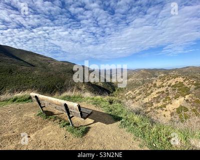 Banc en bois sur le sentier de randonnée dans le parc national de point Mugu, surplombant une partie de la chaîne de montagnes de Santa Monica, Californie.Beaucoup de petits nuages dans le ciel Banque D'Images
