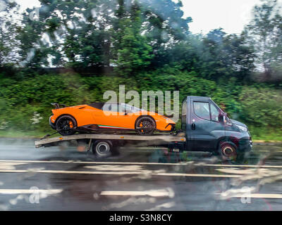 Lamborghini Huracan LP-640 Performante en orange à l'arrière d'un camion-remorque sur autoroute sous la pluie Banque D'Images