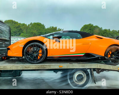 Lamborghini Huracan LP-640 Performante en orange à l'arrière d'un camion-remorque sur autoroute sous la pluie Banque D'Images