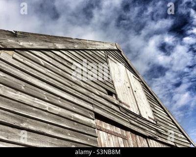 Vue abstraite d'un ancien bâtiment en bois à Thornham, Norfolk, Angleterre contre un ciel bleu et des nuages blancs. Banque D'Images