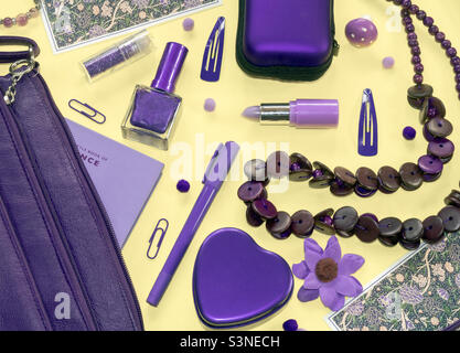 Le contenu violet d'un sac à main violet se déverse sur un fond jaune vif Banque D'Images