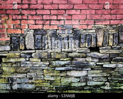 «Juste une autre brique dans le mur» un mur en pierre sèche est clairement bien construit car des briques rouges sont construites directement sur lui pour faire un mur inhabituel en deux tons Banque D'Images