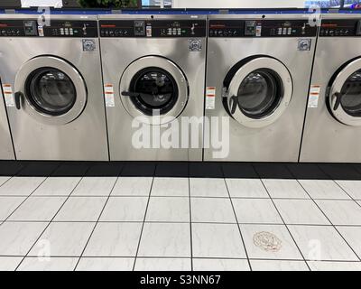 Les lave-linge en acier inoxydable sont installés dans une laverie automatique vide. Banque D'Images