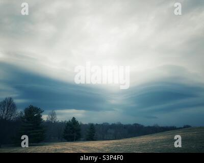 Grande colline, tempête imminente, altostratus gris ondulant des nuages et une ligne saisonnière d'arbres. Banque D'Images