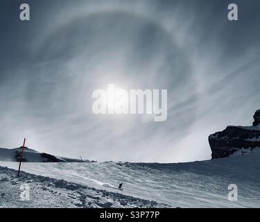 Skieur seul skier sur le Mont Titlis avec un arc-en-ciel circulaire dans le ciel Banque D'Images