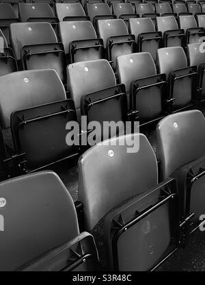 Sièges rouges vides dans un stade de football avant que les supporters ne les occupent le jour du match (noir et blanc) Banque D'Images