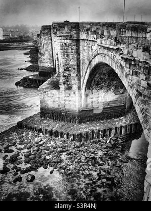 Le pont de Berwick est toujours fier d’avoir été construit dans les années 1600. Le fret maritime traverse l'eau pour donner une atmosphère sinistre à la ville historique de Berwick-upon-Tweed (noir et blanc) Banque D'Images