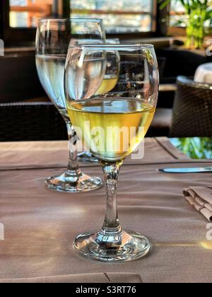 Verre de vin blanc frais sur une table de restaurant au coucher du soleil Banque D'Images