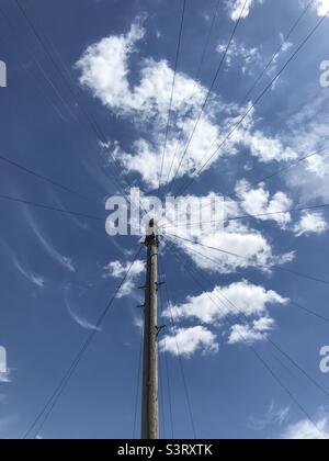 Poteau télégraphique et lignes téléphoniques avec ciel bleu et nuages Banque D'Images