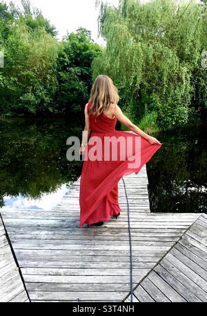 Fille en robe rouge sur un lac, Pologne Banque D'Images