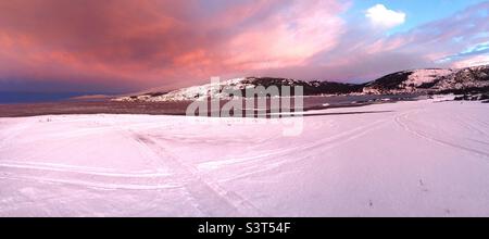 Panorama hivernal dans une mine d'ardoise enneigée pendant que le ciel passe du ciel nuageux au ciel clair. L'Atlantique et les collines sont également visibles. Banque D'Images