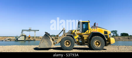 Chargeuse sur pneus dans une carrière de sable au bord d'une rivière Banque D'Images