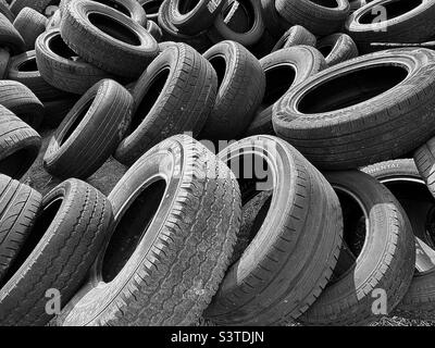 Un tas de pneus anciens et usés se sont accumulés derrière un magasin de voitures/pneus dans l'Utah, aux États-Unis. Désaturer en noir et blanc et ajouter un peu de contraste rend un abstrait intéressant. Banque D'Images