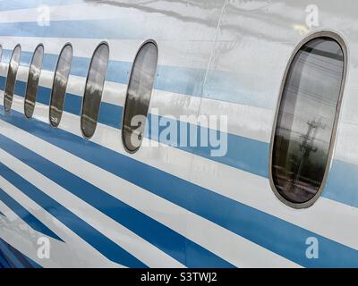 Détails du fuselage de l'extérieur de l'avion passager, avec des bandes bleues et blanches autour des glaces des passagers. Convient pour l'arrière-plan des graphiques et du texte Banque D'Images