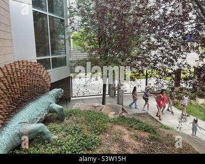 Terrain extérieur au Dinosaur Museum de Vernal, Utah, États-Unis. Un jour de plus, les visiteurs et les touristes se promeunaient tranquillement devant un autre dinosaure de skulking dans l'aménagement paysager. Banque D'Images