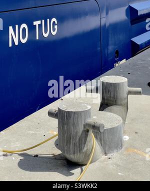 Le côté d'un paquebot de croisière avec les mots «no TUG» à côté d'un quai avec des bollards élégants et modernes. Banque D'Images