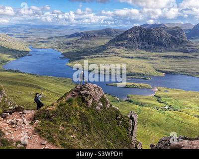 Marcheurs prenant une photo sur la crête de Stac Pollaidh ou Stack Polly, montagne à Inverpolly, avec une vue sur le Loch Lurgainn, nord-ouest de l'Écosse Banque D'Images