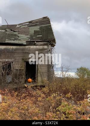 Une citrouille orange vif assise sur le rebord de la fenêtre d'une maison abandonnée. Scène effrayante d'une maison hantée. Banque D'Images