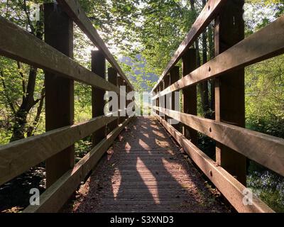 Vue le long d'un pont à lamelles en bois illuminé par la lumière du soleil tôt le matin Banque D'Images
