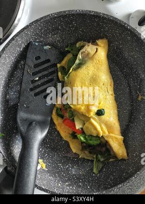 Omelette faite maison dans une casserole avec fromage, tomate et feuilles de salade Banque D'Images
