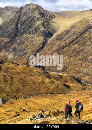 Marcheurs sur le chemin et les pentes de Munro Buachaville Etive Beag, avec vue sur la crête d'Aonach Eagach, Glencoe, Écosse Banque D'Images