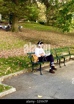 Personnes assises dans le parc en automne au milieu de feuilles mortes Banque D'Images