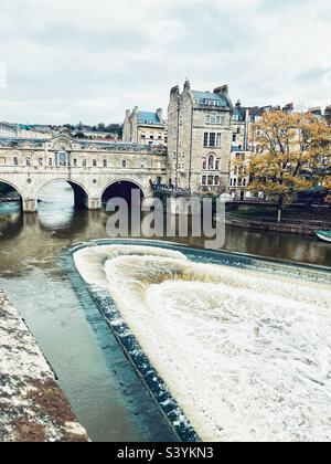 Pont Pulteney sur la rivière Avon à Bath, Angleterre. Le pont est l'un des quatre seuls dans le monde qui a des magasins sur toute sa travée des deux côtés. Déversoir en fer à cheval au premier plan. Banque D'Images