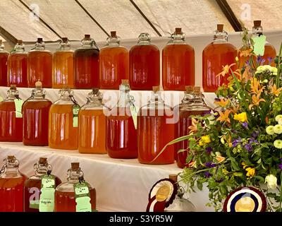 Une sélection de bocaux en verre remplis de cidre délicieux dans une variété de couleurs de miel doré sur l'exposition pour juger au Devon County Show dans le pays ouest de l'Angleterre, en été Banque D'Images