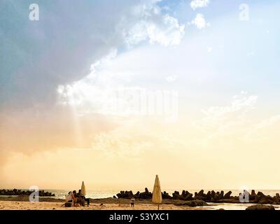 Le soleil se pageant à travers les nuages sur la plage Banque D'Images