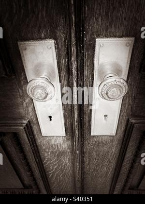 Boutons de porte en métal d'époque dans l'ancien bâtiment de Manhattan, New York. Photo en noir et blanc, montrant une partie des portes en bois. Banque D'Images