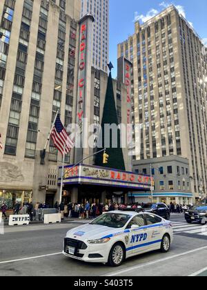 New York, New York, Etats-Unis – 26 novembre 2022: Radio City Music Hall avec arbre de Noël au sommet du chapiteau. Voiture de police de New York (NYPD) devant la photo. Banque D'Images