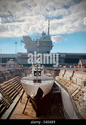 Vue de face du HMS M33 au chantier naval historique de Portsmouth, avec le porte-avions de la Royal Navy HMS Queen Elizabeth amarré derrière Banque D'Images