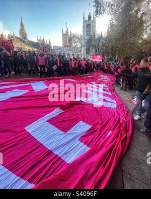 Immense drapeau rose sur le terrain lors de la manifestation de l'UCF sur la place du Parlement de Londres avec l'abbaye de Westminster et la Chambre des Lords en arrière-plan - grève postale le 2022 décembre Banque D'Images