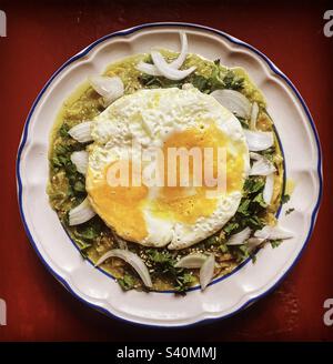 Deux œufs frits sur des chilaquiles vertes avec oignon pour le petit déjeuner au Mexique Banque D'Images